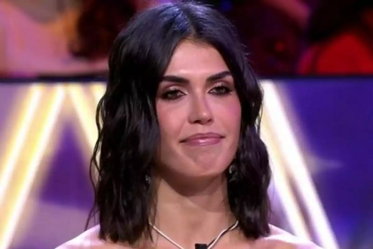 Sofía Suescun con cabello oscuro y ondulado, usando un collar y un micrófono, en un entorno iluminado en De Viernes. Sofía Suescun con cabello oscuro y ondulado, usando un collar y un micrófono, en un entorno iluminado en De Viernes.